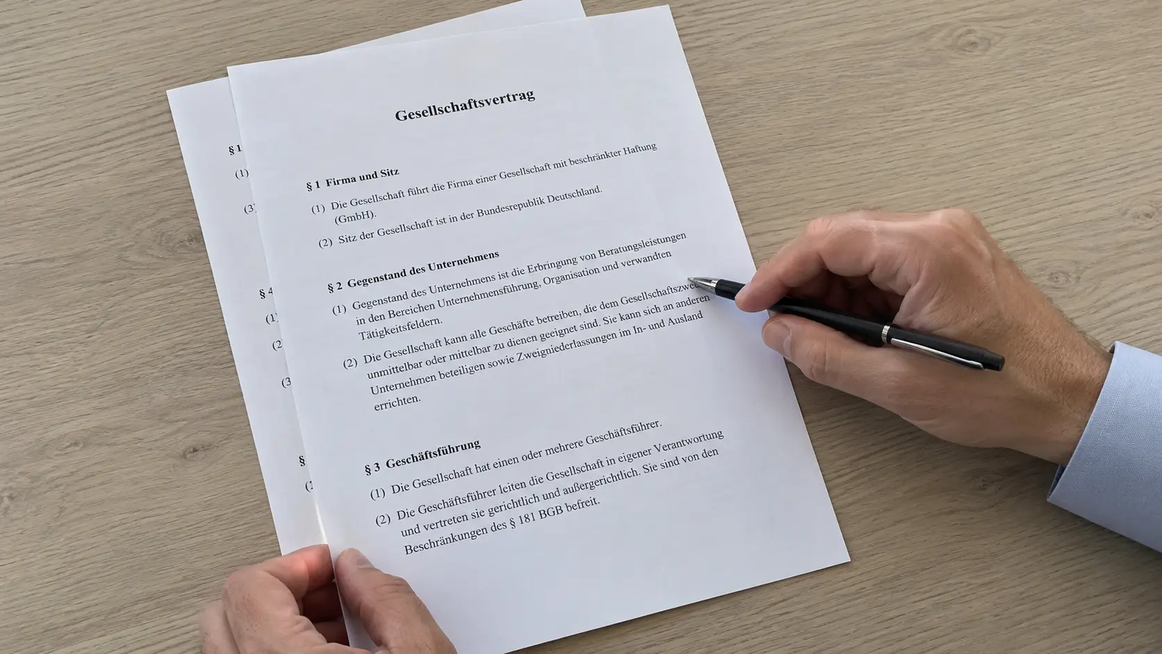 Hand mit Kugelschreiber prüft den Gesellschaftsvertrag einer GmbH auf einem Holztisch, aufgeschlagen bei Firma, Gegenstand und Geschäftsführung